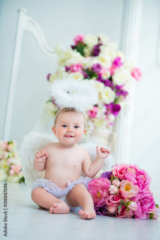 Little angel smiling and happy sitting on the background of flowers and harp