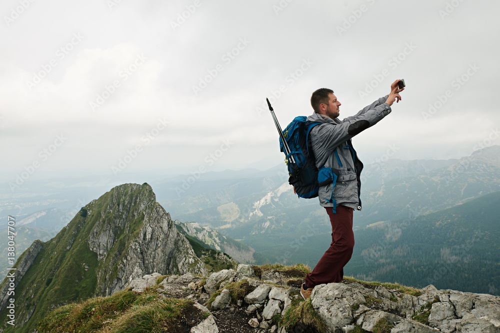 Hiker taking photos from high atop a mountain Hiker taking photos from high atop a mountain