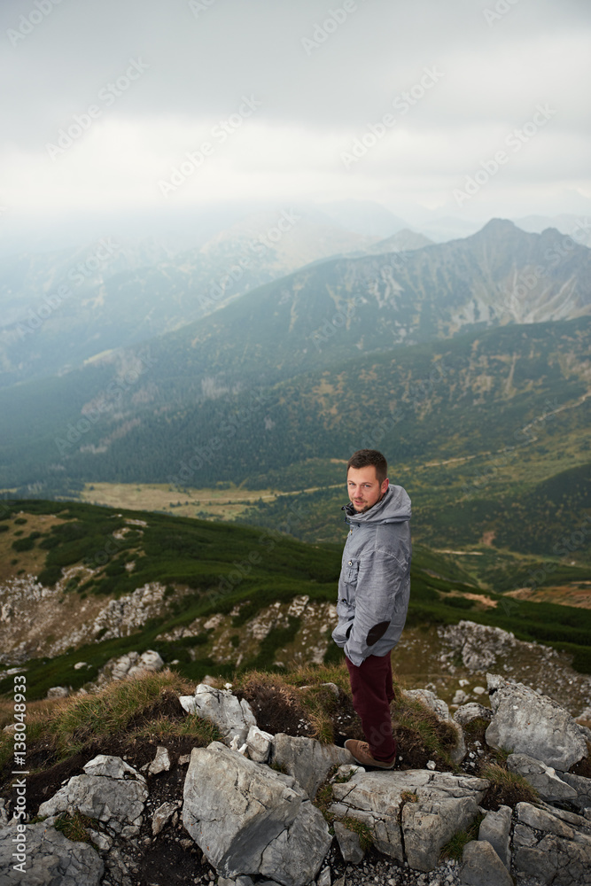 Man standing on a peak overlooking the mountains