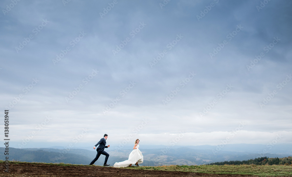 Obraz premium The charming brides running along field