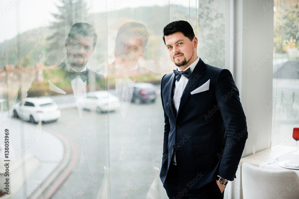 Fototapeta premium Thoughtful brunette man stands before panoramic window in restaurant hall