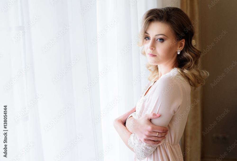 The beautiful  bride stands near window