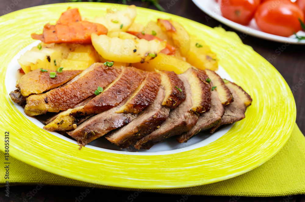 Roast goose breast fillet with potatoes rustic style on a plate on a dark wooden background. Close up