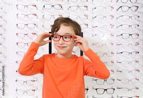 Obraz na płótnie optician putting glasses to boy at optics store
w salonie