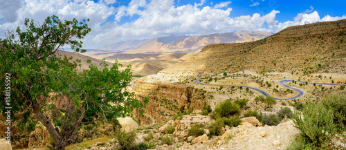 Obraz na płótnie road winding along the mountain gorge in the southern part of Iran, green bushes grow on slopes, a set of beautiful clouds in the sky w salonie
