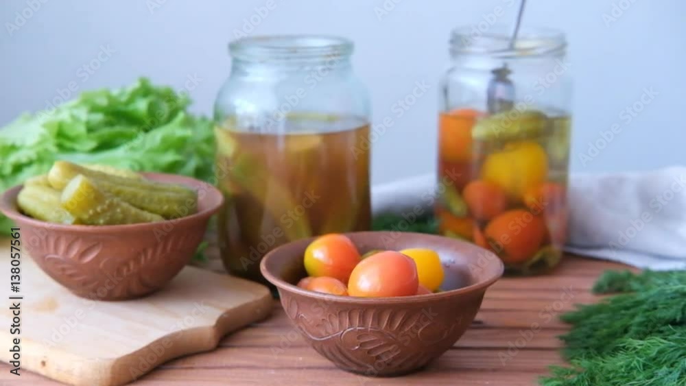 Woman getting pickled tomatoes and cucumbers out of the glass bottle with a fork Woman getting pickled tomatoes and cucumbers out of the glass bottle with a fork