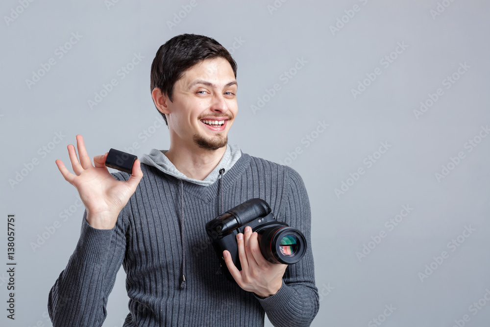 young smilling photographer in shirt holds the battery for DSLR young smilling photographer in shirt holds the battery for DSLR