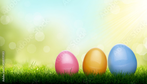 Decorated Easter Eggs  blades of Green Grass with a blurred bokeh sky blue and green garden foliage background.