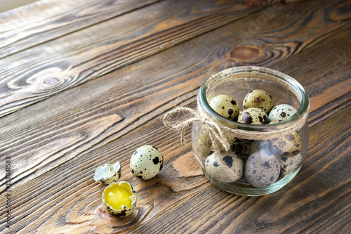 Fresh quail eggs in a glass jar,decorated with a linen rope, kitchen wooden table
