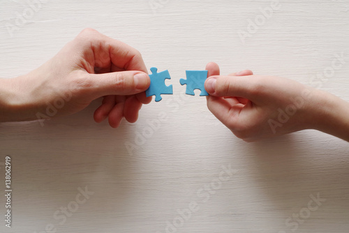 Puzzles. Hand of the child and hand of mother fold puzzle, closeup, top view