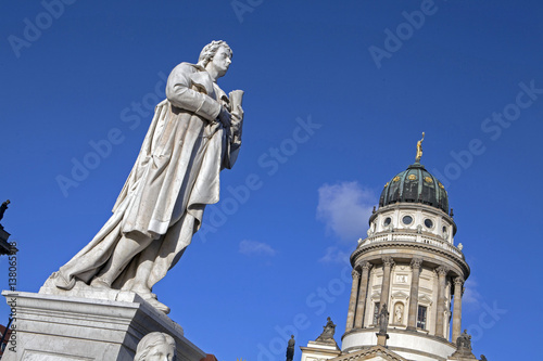 Berlin gendarmenmarkt. Statue of Friederich Schiller and Dome of a church.