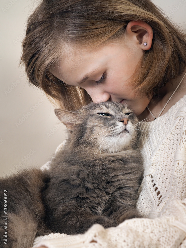 Girl and cat. Young girl kisses a gray cat