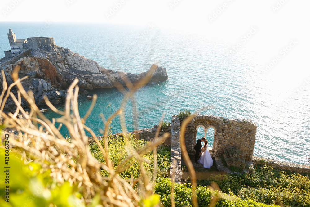 Groom and bride near a window to the sea