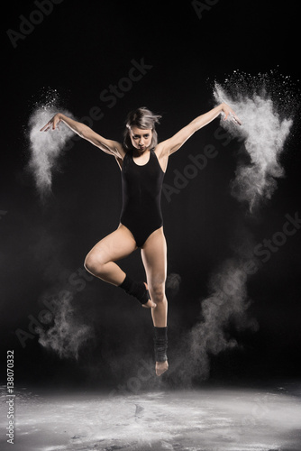 concentrated woman in bodysuit with dust jumping on black © LIGHTFIELD STUDIOS