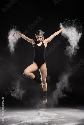 concentrated woman in bodysuit with dust jumping on black