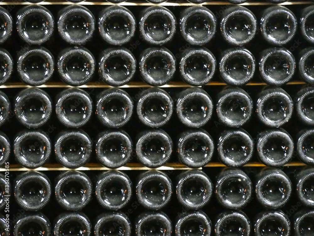 Old bottles of wine in rows in wine cellar. Rows of many wine bottles in winery cellar storage. Beautiful texture or background. Close up Old bottles of wine in rows in wine cellar. Rows of many wine bottles in winery cellar storage. Beautiful texture or background. Close up