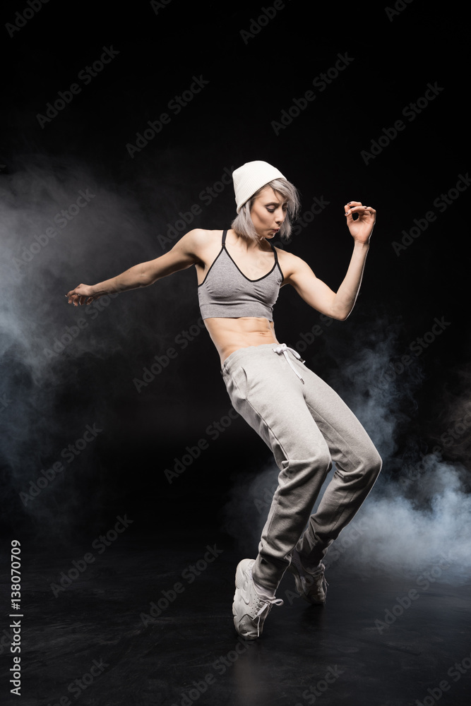 woman in sports clothing dancing on black