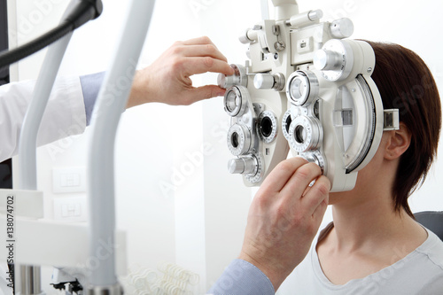 woman doing eyesight measurement with optical phoropter photo