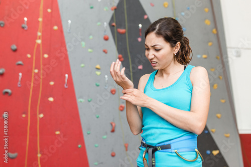 woman climber with the trauma and pain in the wrist on a background of climbing wall