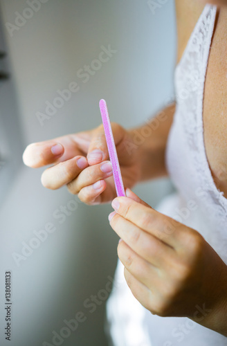Young woman doing yourself a manicure. Hands of the girl close-up with nail file.