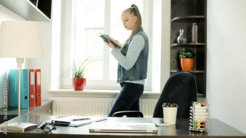 Girl standing next to the window in her office and reading book, steadycam shot
Girl standing next to the window in her office and reading book, steadycam shot
