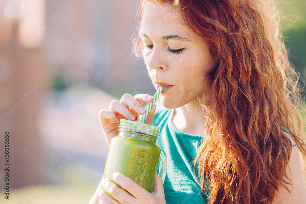 red hair woman drinking with a straw a healthy green juice red hair woman drinking with a straw a healthy green juice