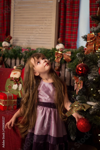 Girl stands near a Christmas tree and looking up