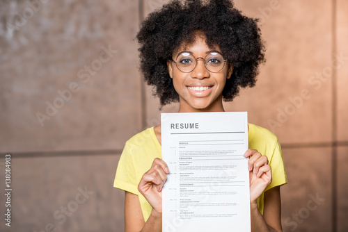 Portrait of a young african woman holding resume document indoors photo