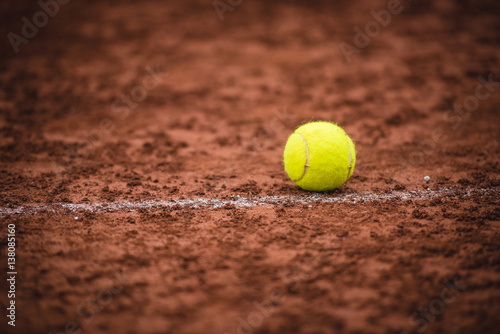 Bright yellow tennis ball lying on the court ground. Horizontal outdoors shot. © progat