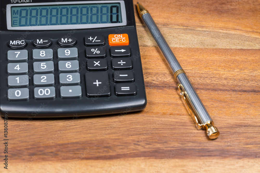 Calculator and ballpoint pen on wooden background. Calculator and ballpoint pen on wooden background.