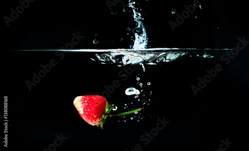 Strawberry falling in water isolated against a black background,Strawberry falling in water