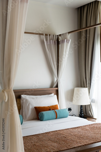 resort style bedroom with white sheet, brown and blue pillow