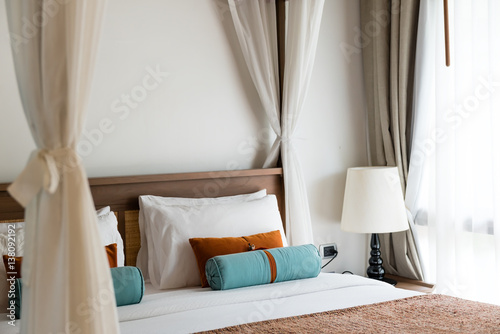 resort style bedroom with white sheet, brown and blue pillow