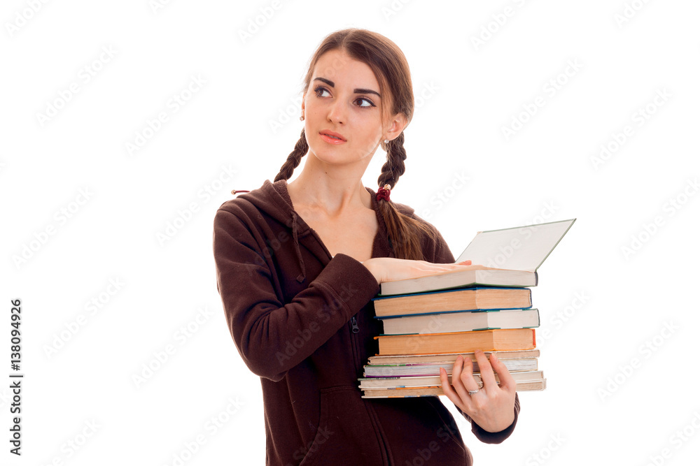 young pretty brunette student girl in brown sport clothes with pigtails and books in her hands looking away isolated on white background young pretty brunette student girl in brown sport clothes with pigtails and books in her hands looking away isolated on white background