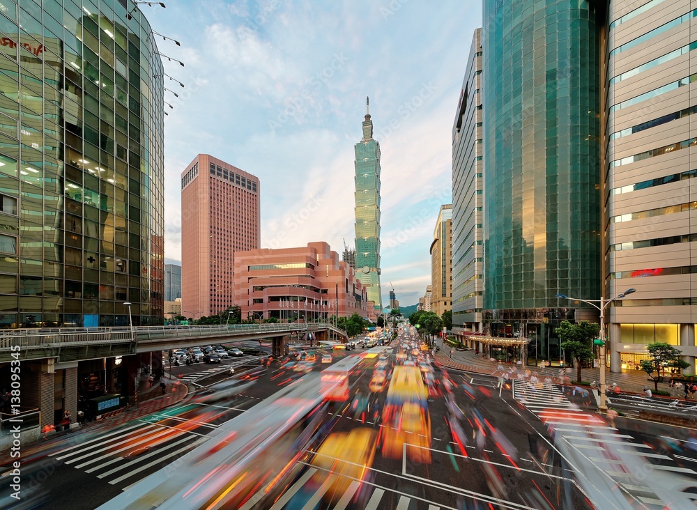 Fototapeta premium Panoramic view of a street corner in Taipei City with busy traffic trails at rush hour ~ Beautiful night scenery of Taipei 101 Tower and World Trade Center in XinYi commercial area in Taipei downtown