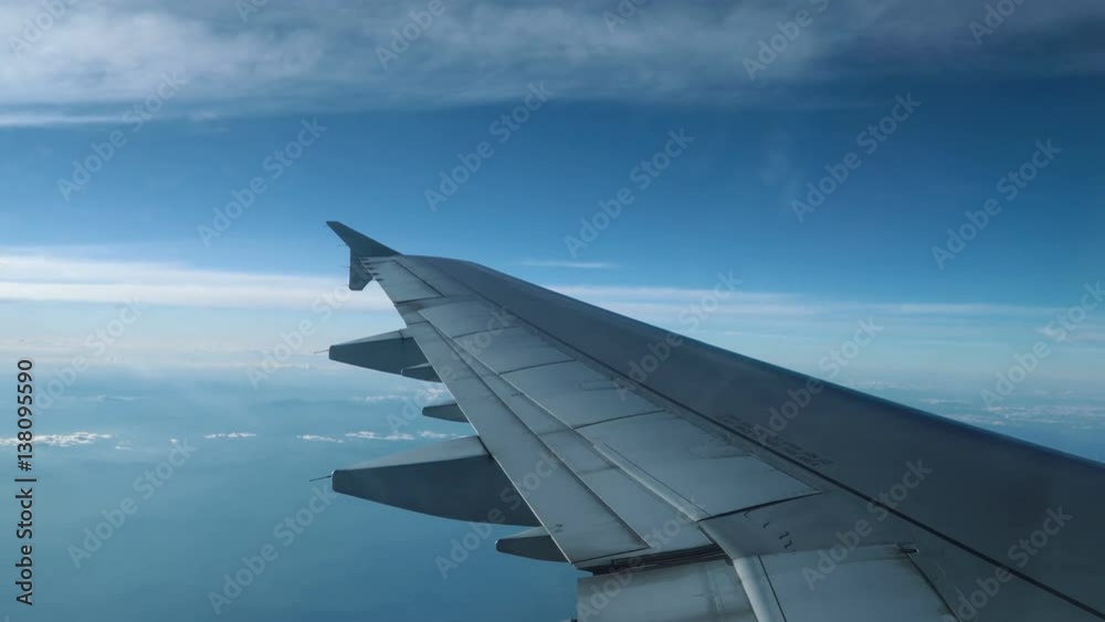 Wing of airplane flying above clouds in the sky - the view through the window. 4K stock footage.
Wing of airplane flying above clouds in the sky - the view through the window. 4K stock footage.