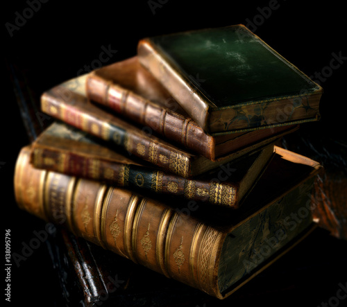 Old, vintage books stack in directional light with selective focus effect.