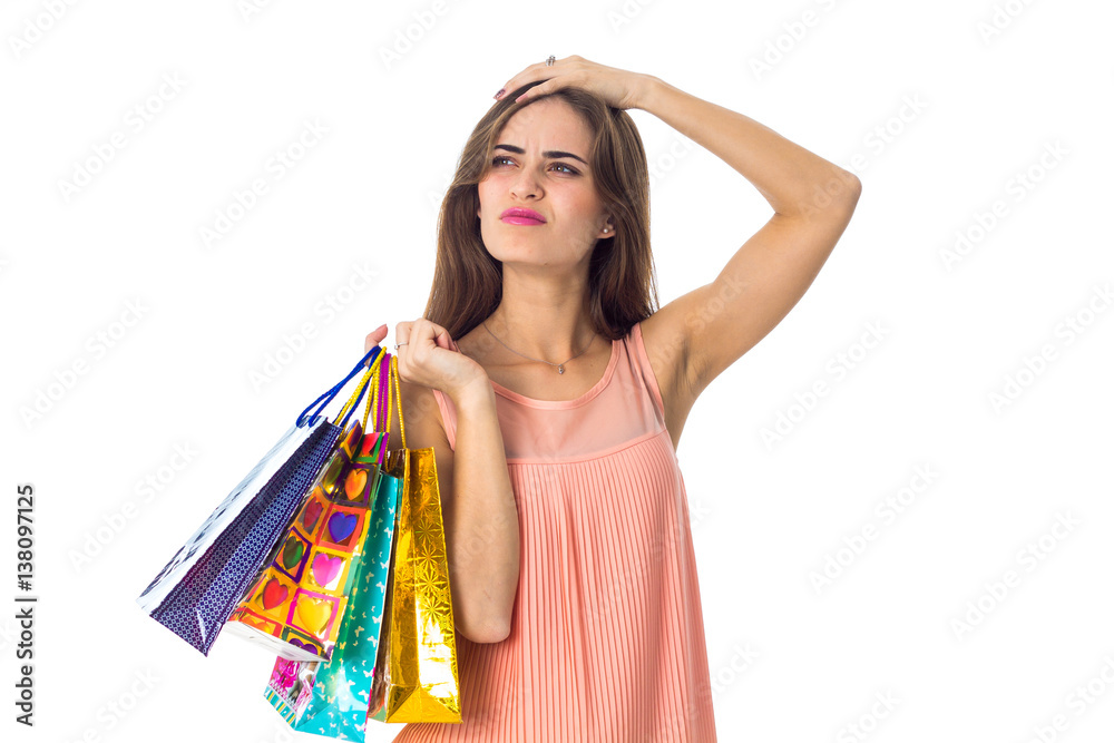 serious young girl keeps a hand behind her head and bags isolated on white background serious young girl keeps a hand behind her head and bags isolated on white background