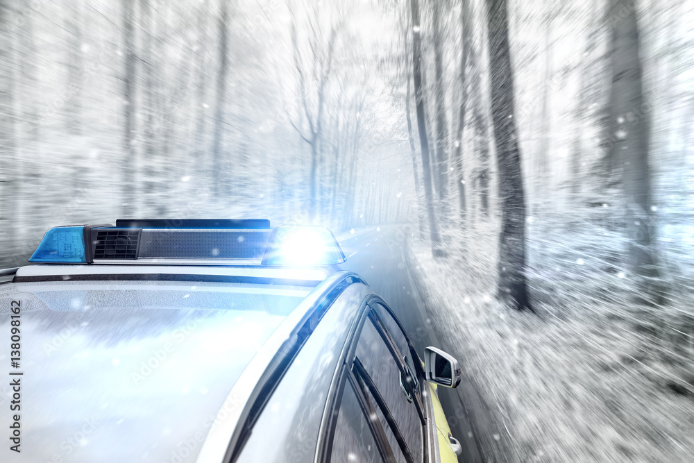 Polizeiauto bei Schneefall auf Landstraße Polizeiauto bei Schneefall auf Landstraße