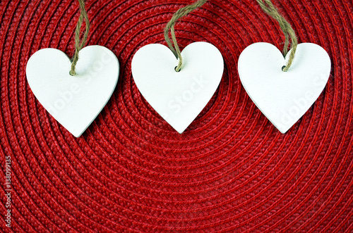 Decorative white wooden hearts on red straw napkin background with copy space.