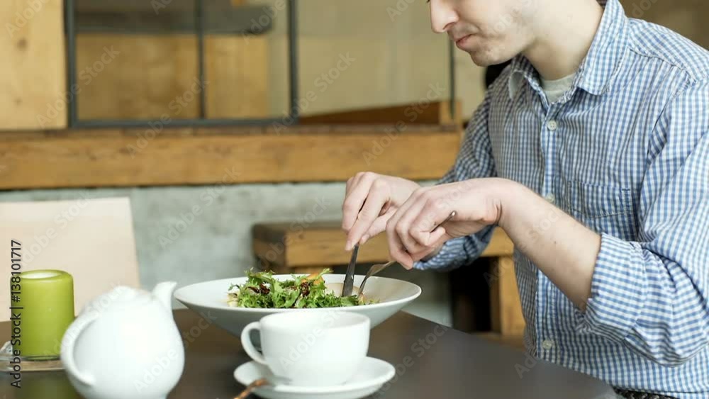 Young man sitting in the cafe and eating fit, healthy lunch, steadycam shot
