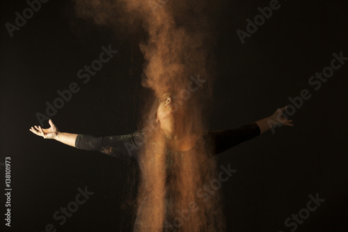 Rain of orange dust upon an indian woman dancing to holi festival isolated on black background