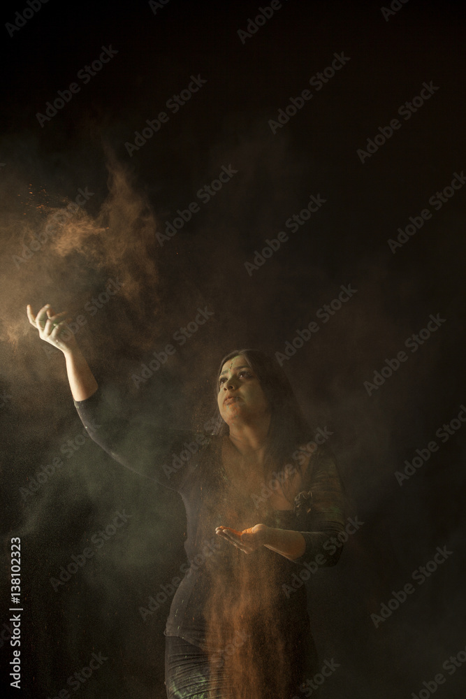 indian woman dancing to holi festival and throwing colored dust isolated on black background