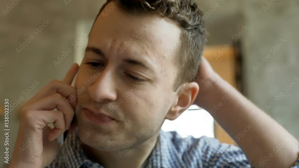 Young man sitting in the cafe and talking with someone on cellphone
Young man sitting in the cafe and talking with someone on cellphone