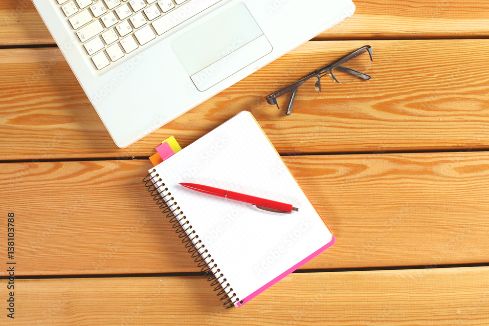 surface of a wooden table with notebook, smartphone, eye glasses, and pen surface of a wooden table with notebook, smartphone, eye glasses, and pen