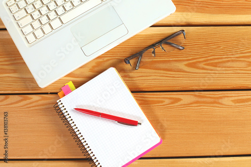 surface of a wooden table with notebook  smartphone  eye glasses  and pen