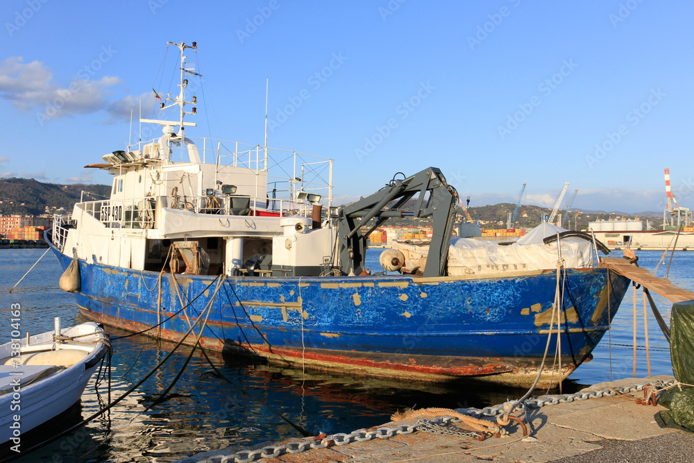 Old blue and white fishing boat docked in the harbour of La Spezia in Italy.