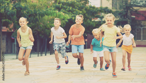 Group of smiling children running together in town on summer