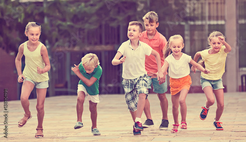 Group of friendly children running together in town on summer
