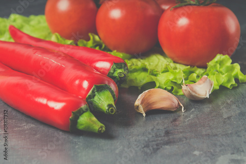 Red chili peppers, tomatoes, Sadat and garlic on a gray marble background. photo